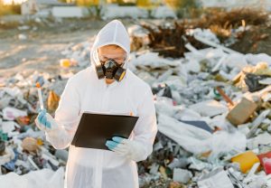 Man in coveralls at trash pill. Doing research. Concept of ecology, environmental pollution.